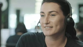 A smiling woman wearing a telephony headset. 