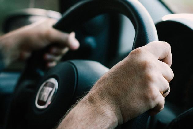 Persons hands on a steering wheel