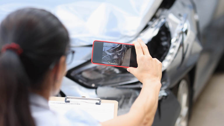 Person taking photo of damage to car bonnet