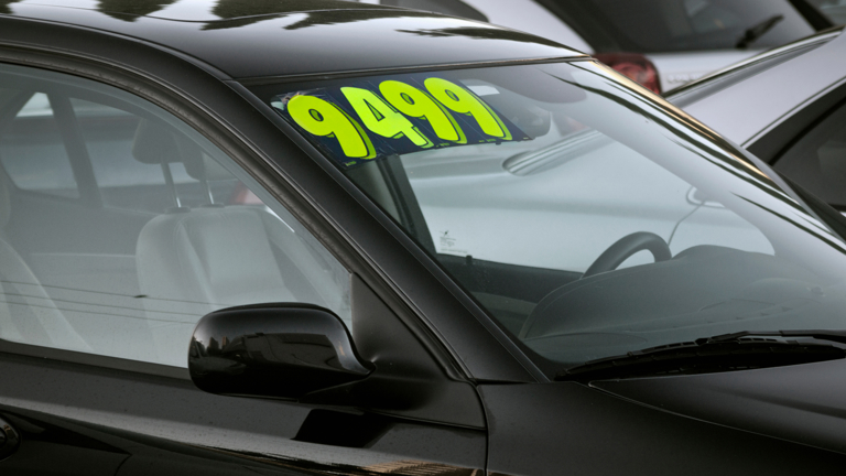 Secondhand car parked in a car dealership with price marked on the windscreen