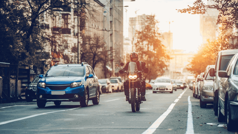 Car and motorcycle driving next to one another on a city road