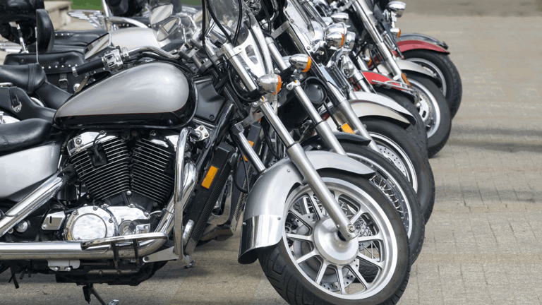 Motorcycles lined up on the footpath outside a shop