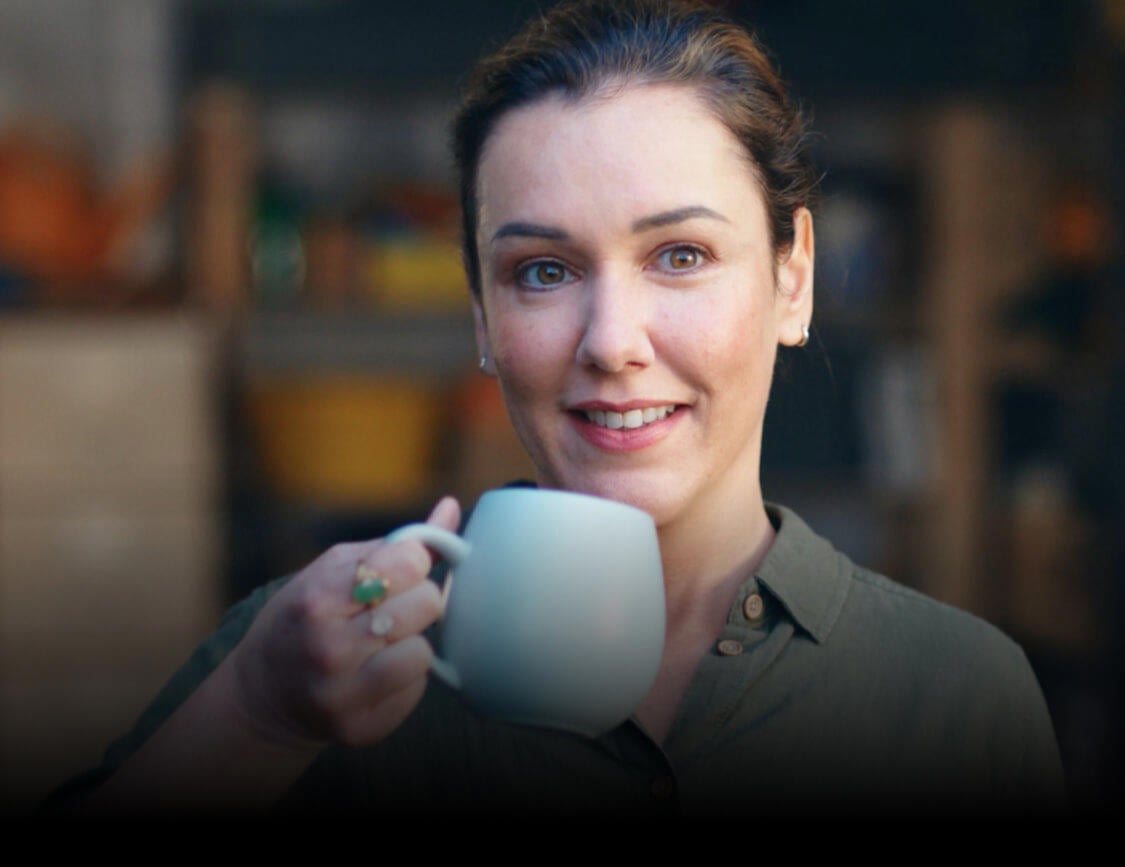 Woman smiling contently while sipping on a cup of tea