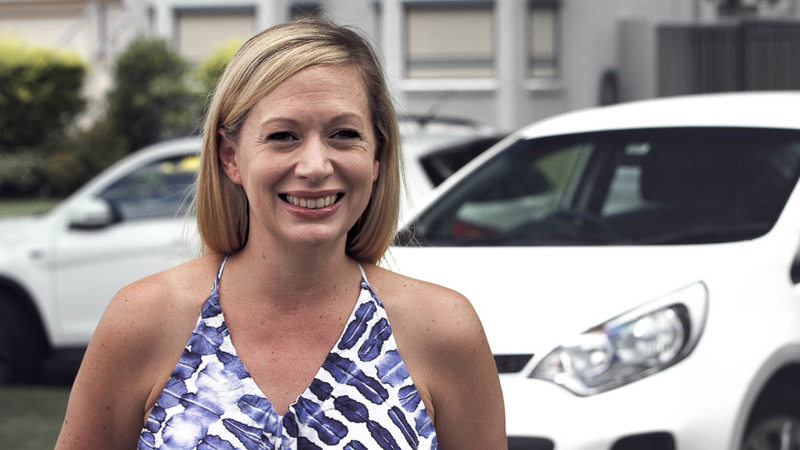 Nicole smiling in front of car