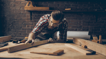 Man measuring up wooden planks in a workshop