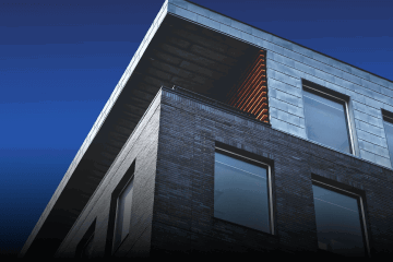 Image of the corner of a building with the bright blue sky as a backdrop