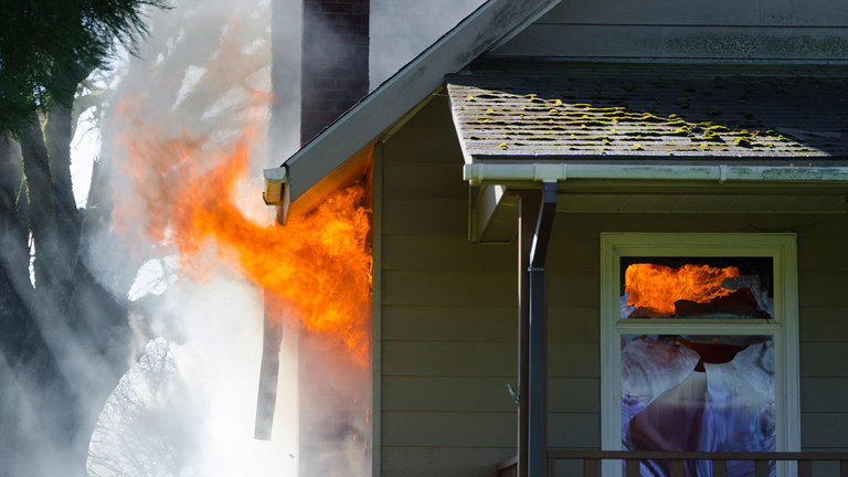 House on fire with flames and smoke billowing out of windows