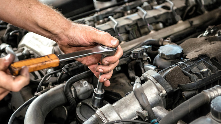 Mechanic checking the oil level on a dipstick from a car engine