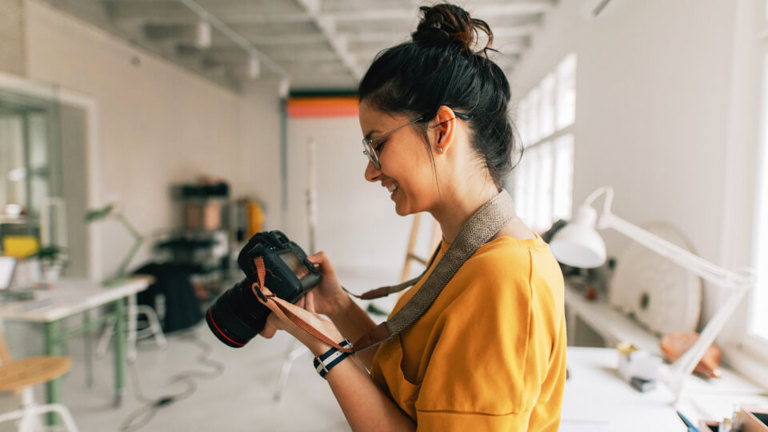 A woman looking at photos on her camera, contemplating whether she needs camera insurance