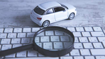 A toy car next to a keyboard and a magnifying glass.