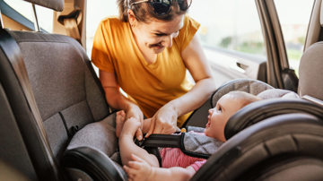 A mother securing her baby in a child's car seat