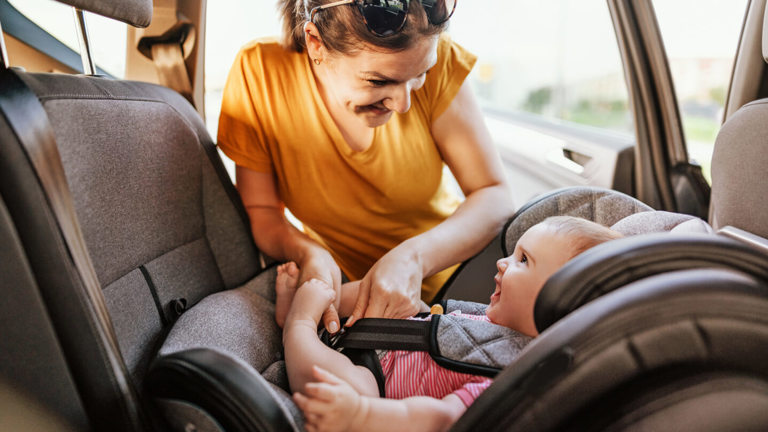 A mother securing her baby in a child's car seat