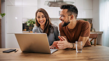 A couple looking for information on a first home buyer loan on a laptop