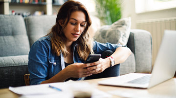 A woman researching the First Home Super Saver Scheme using her phone and laptop