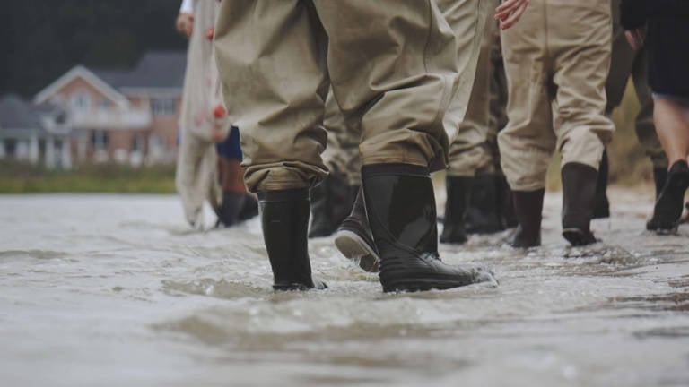 People wearing gum boots standing in flood water