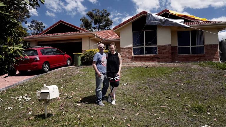 Michael and Saffron standing in front of their home during the repair process
