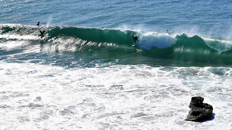 Surfer getting pitted near rocks