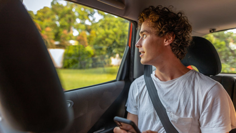 A young man getting a ride in a car insured for ridesharing.