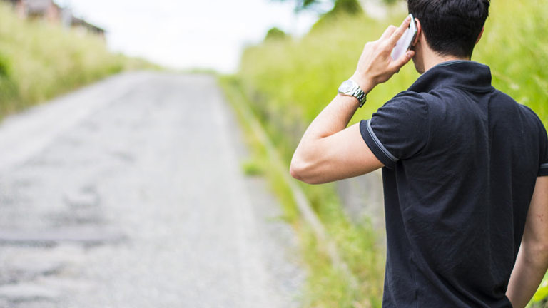 Man on mobile phone at the side of the road