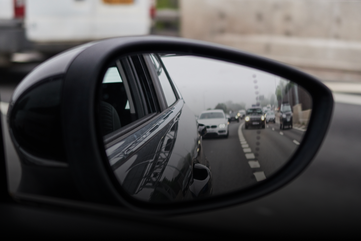 A view from a rear vision mirror of other vehicles on the road.