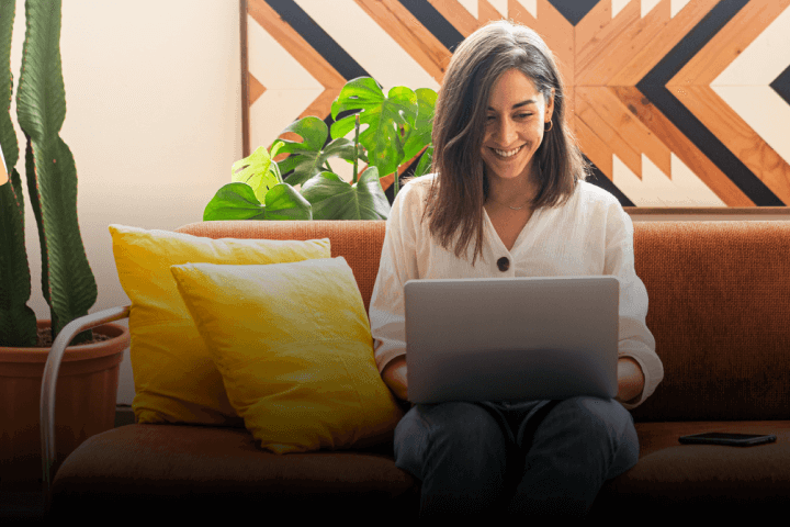 A woman with a laptop sitting on a couch.