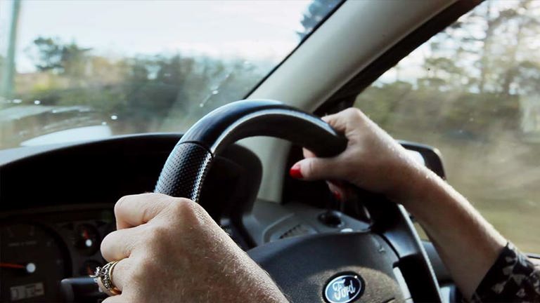 Someone holding a cars steering wheel